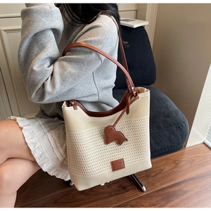 Detail of knit tote bag featuring a leather dog charm and brand logo patch