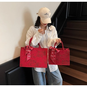 Detail view of large and small red floral jacquard tote bags with wedding ribbon bows