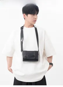 Detail of minimalist black leather mini crossbody bag with industrial buckle and wide strap