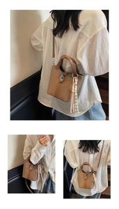 Detail of woven brown bucket bag with leather trim and decorative bag charm on a strap