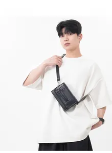 Detail view of the sleek black rectangle crossbody bag featuring polished silver hardware