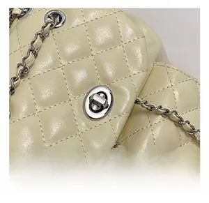 Detail of silver twist lock and quilted leather texture on beige crossbody chain bag