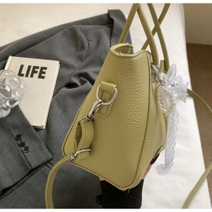 Détail du cabas en cuir vert citron avec boucles argentées et pendentif en dentelle