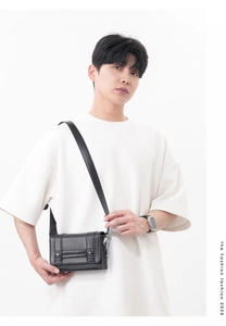 Detail of a matte black leather shoulder bag showing the flap closure and vertical straps