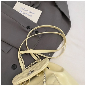 Detail of quilted diamond pattern and golden twist lock on cream leather backpack