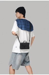 Detail of a minimalist black PU leather crossbody bag with a metal buckle on a model