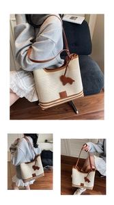 Detail of beige woven tote bag featuring brown leather trim and cute animal charm