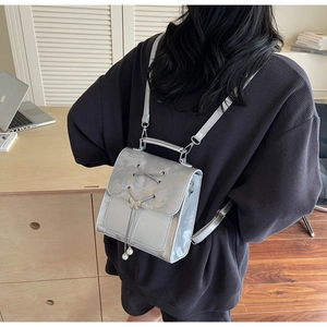 Silver metallic backpack with butterfly buckle and pearl charms shown on a person