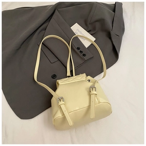 Detail of light yellow quilted mini backpack with silver buckles and flap design