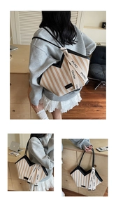 Close-up of beige diagonal stripe tote bag featuring decorative branded fabric straps
