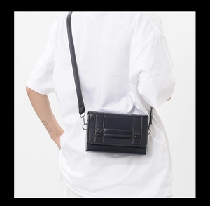 Detail of a black rectangular crossbody bag showing the matte finish and detachable strap