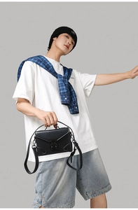Detail showing a matte black PU leather crossbody bag worn by a male model in casual style