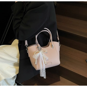 Détail du sac cabas rose en cuir avec élégante breloque en perles et dentelle