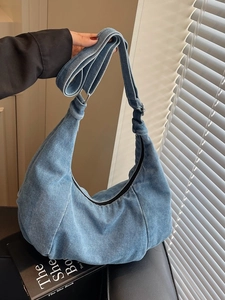 Retro light blue denim hobo bag with adjustable strap shown against a minimalist wall