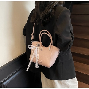 Détail du sac bandoulière rose texturé avec nœud en dentelle blanche et perles décoratives