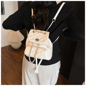 Rear view of a white quilted mini backpack with silver chain straps and flap closure