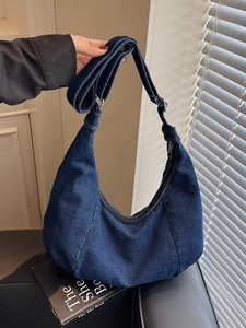 Retro dark blue denim hobo bag with adjustable strap shown in a cozy indoor setting
