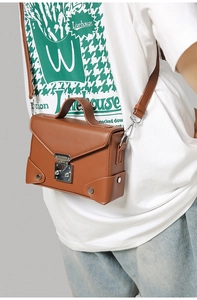 Close-up of brown PU leather envelope bag featuring silver buckle and retro metal rivets