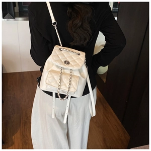 Close-up of white quilted mini backpack with silver metal twist lock and chain strap