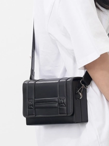 Minimalist black box crossbody bag with wide shoulder strap and matte leather finish