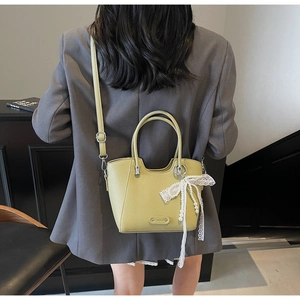 Détail du sac cabas en cuir grainé vert clair avec nœud en dentelle et chaîne de perles
