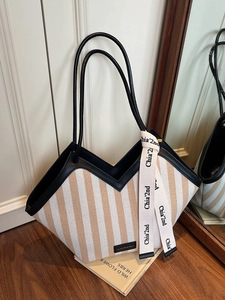 Striped canvas tote bag with black leather handles and decorative silk scarf in a lifestyle setting