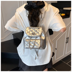 Silver quilted metallic backpack with chain straps and turn-lock closure on model