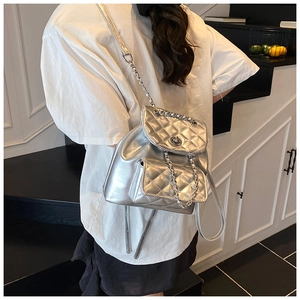 Silver quilted backpack with metallic chain straps shown on model in a modern style