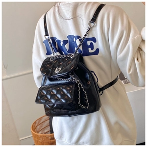 Detail of black quilted leather backpack with woven chain straps and front pocket