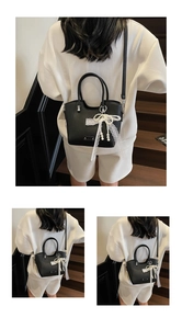 Détail d'un cabas noir en cuir grainé avec nœud en dentelle blanche sur un mannequin