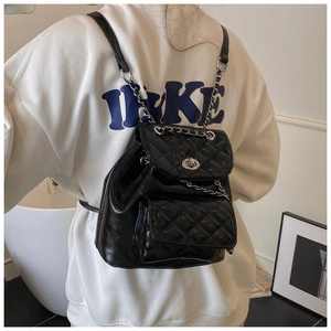 Detail of black quilted chain backpack with silver-tone metal turn-lock closure
