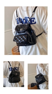 Detail view of black quilted chain backpack with silver twist lock and glossy leather finish