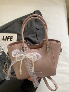 Sac à main en cuir rose avec nœud perlé et dentelle sur fond de blazer gris chic