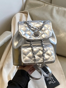 Silver quilted metallic backpack with chain straps and turn-lock closure in lifestyle setting
