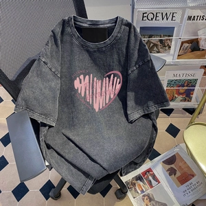Macro shot of washed gray t-shirt featuring pink heart graphic and distressed vintage texture