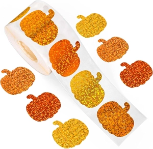 Macro shot of pumpkin-shaped stickers with orange glitter texture in roll format