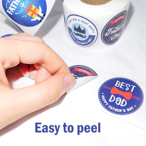 Action shot showing a hand peeling a round Father's Day sticker from a large roll