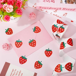 Roll of laser strawberry stickers with glitter finish on pink envelope for gift sealing
