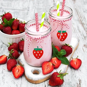 Close-up of strawberry laser stickers on glass jar with decorative rope and straw