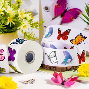 Roll of 500 waterproof butterfly stickers with colorful patterns on wood tray