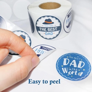 Detail showing hand peeling a round Father's Day sticker from the roll, easy to use