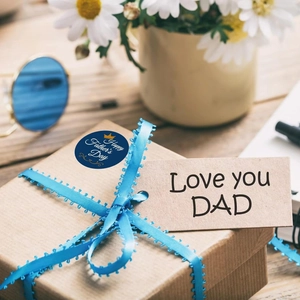 Detail of Father's Day gift box with blue ribbon, thematic seal sticker and kraft tag