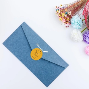 Detail of yellow smiley thank you sticker sealing a navy blue textured envelope