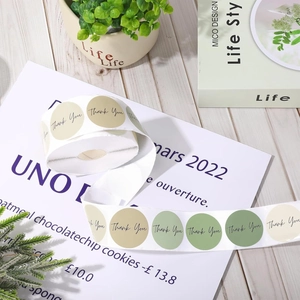 Detailed view of earth tone Thank You labels for gift packaging on a rustic wooden roll
