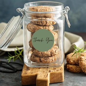Macro detail of round dark green Thank You sticker on a glass jar with cookies
