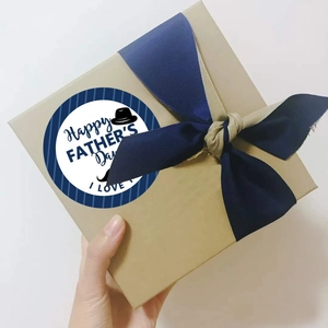 Close-up of Happy Father's Day sticker on kraft gift box with blue ribbon bow
