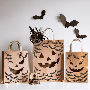 Three Halloween kraft gift bags featuring black glitter pumpkin faces and spider details