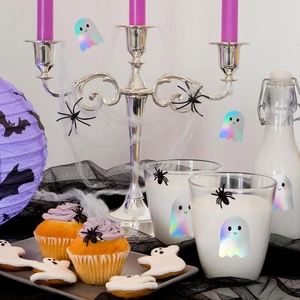 Close-up of holographic ghost stickers and Halloween party decor on cups and bottles