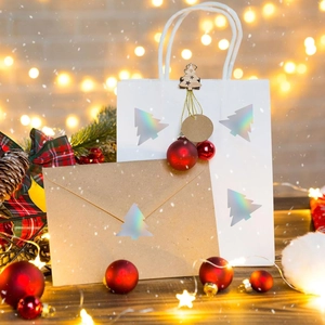 Close-up of holographic Christmas tree gift bag and kraft envelope with festive ornaments