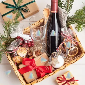 Elegant wicker gift basket with wine glass and holiday treats on a white wooden table